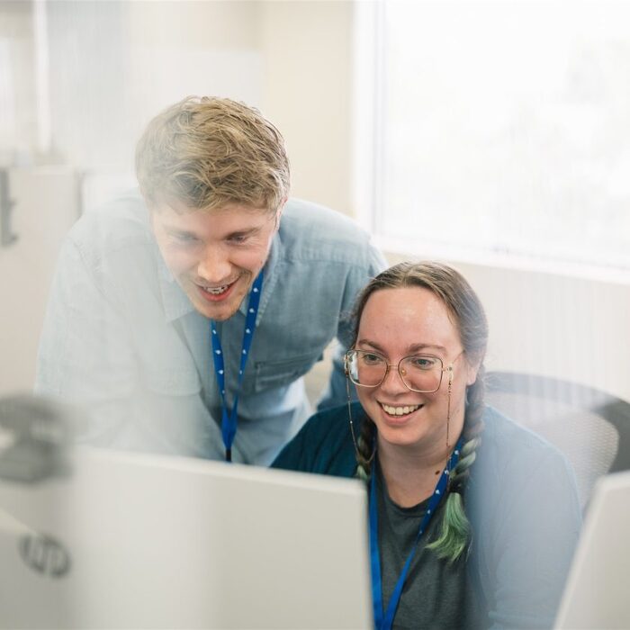 Two Milwaukee Electronics team members working together at a computer