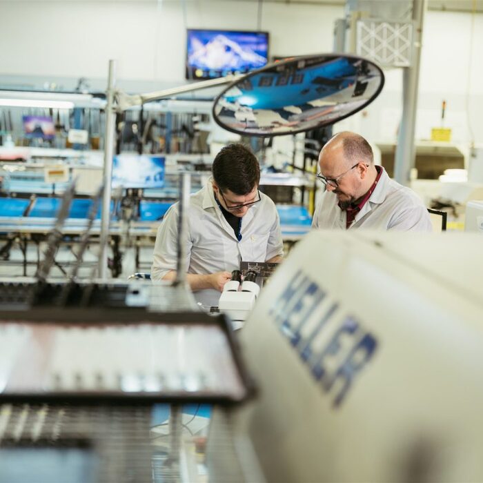 Two Milwaukee Electronics technicians inspecting an assembly on the production floor